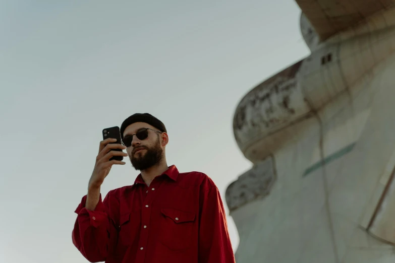 a man in a red shirt taking a picture of himself, a picture, by Lee Loughridge, pexels contest winner, thin beard, reflection of phone in visor, vintage aesthetic, shaved temple