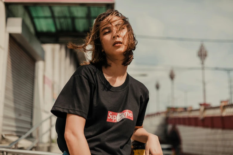 a young man sitting on top of a skateboard, a portrait, by Julia Pishtar, trending on unsplash, wearing a black t-shirt, supreme, vietnamese woman, promotional image