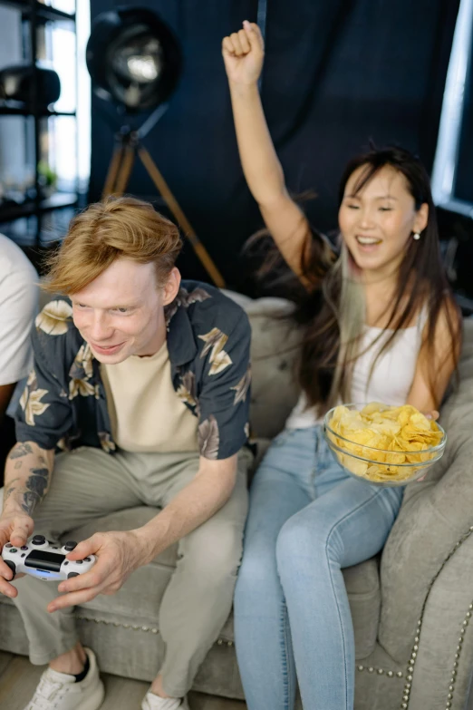 a group of people sitting on top of a couch, a picture, playing games, eating chips and watching tv, promotional image, male and female