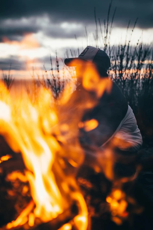 a person sitting in front of a fire, pexels contest winner, al fresco, profile image, field on fire, up close shot