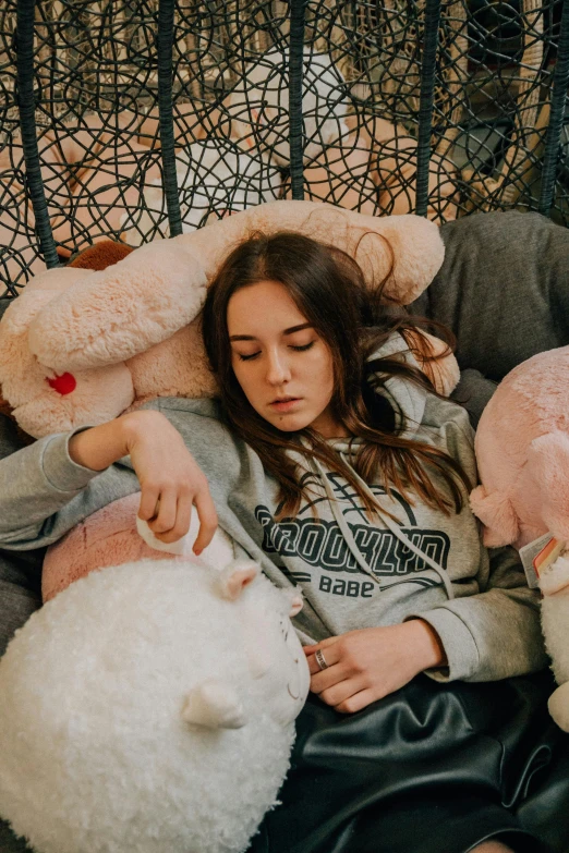 a woman laying on a couch with a bunch of stuffed animals, inspired by Elsa Bleda, trending on pexels, portrait of depressed teen, pink, softplay, hailee steinfeld