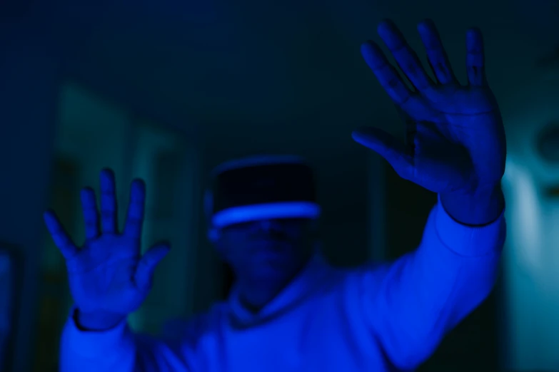 a man wearing a virtual reality headset in a dark room, a hologram, pexels, hands up, vibrant blue, aesthetic shot, avatar image