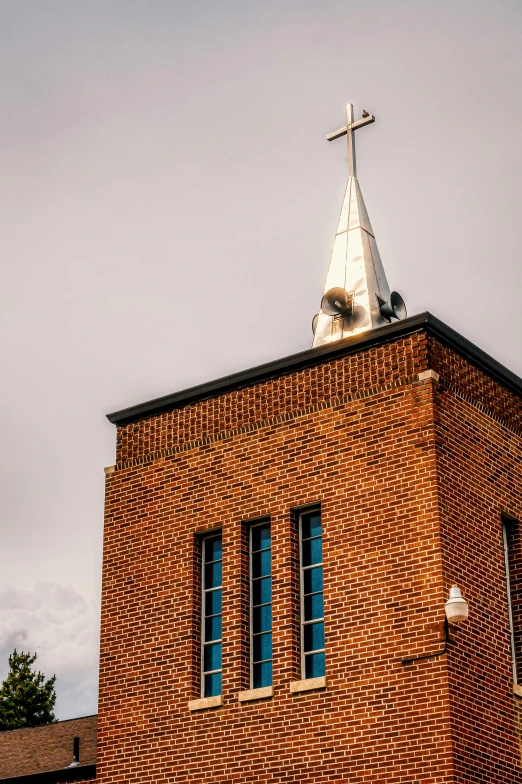 a church steeple with a cross on top, unsplash, modernism, brick building, high detail photograph, color photo, multiple stories