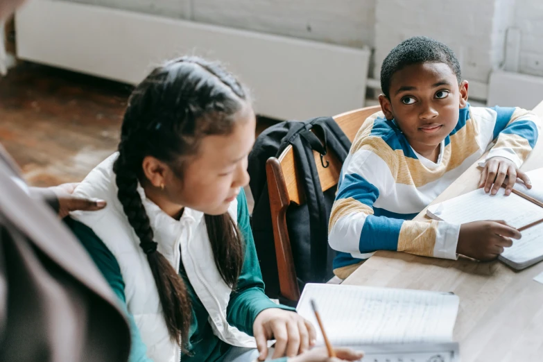 a group of children sitting around a wooden table, textbooks and books, portrait featured on unsplash, medium shot of two characters, promotional image