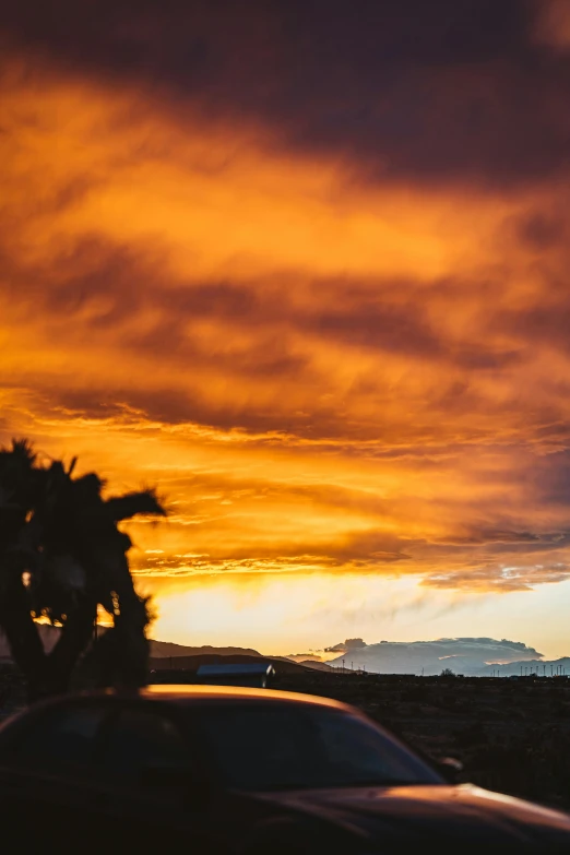 a car parked on the side of the road at sunset, by Robbie Trevino, dramatic swirling clouds, palm springs, cinematic shot ar 9:16 -n 6 -g, super detailed