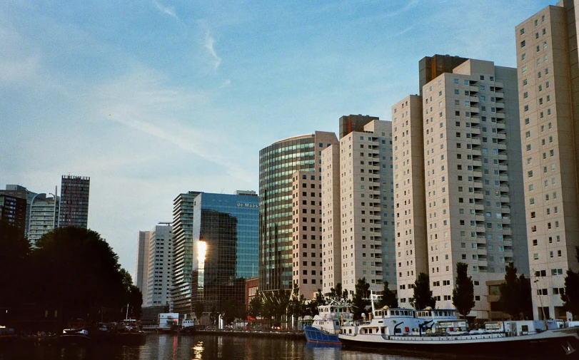a boat floating on top of a river next to tall buildings, a photo, inspired by Ricardo Bofill, pexels contest winner, modernism, kodak portra 400, helmond, walter gropius, 2000s photo