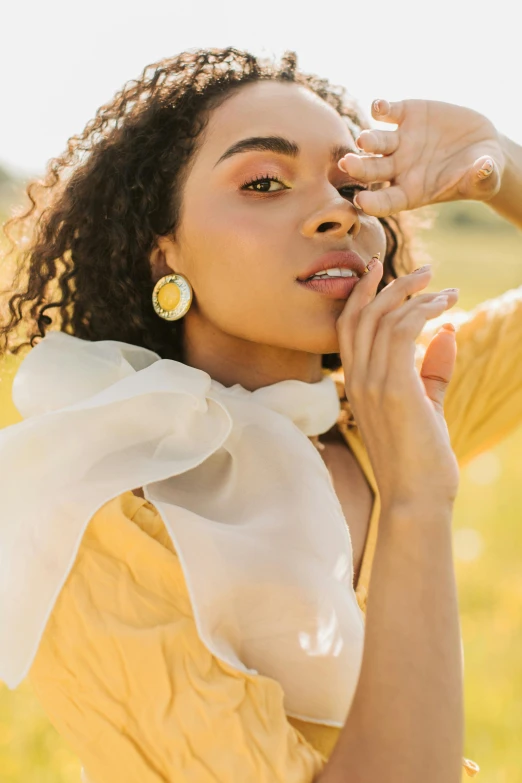 a woman in a yellow dress standing in a field, a portrait, by Winona Nelson, trending on pexels, renaissance, earrings, fashion editorial, flowing golden scarf, ashteroth