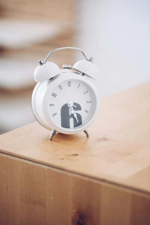 an alarm clock sitting on top of a wooden table, by Nick Fudge, happening, glossy white metal, letter s, official product photo, bells