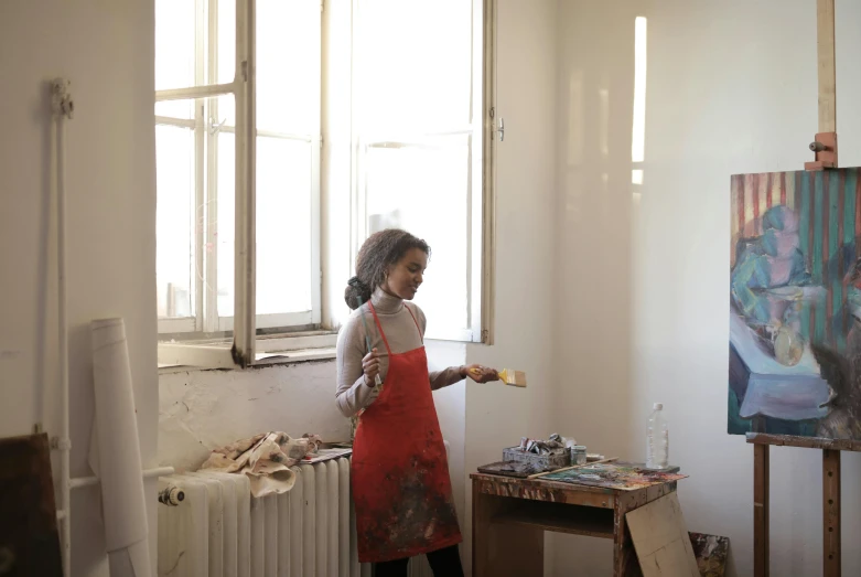 a woman that is standing in front of a painting, near a window, working, faridah malik, apartment