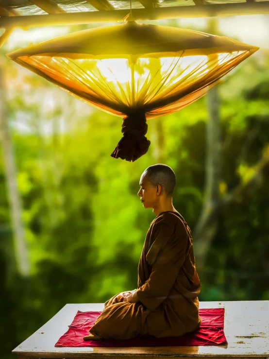 a man sitting in a meditation position under an umbrella, thawan duchanee, avatar image