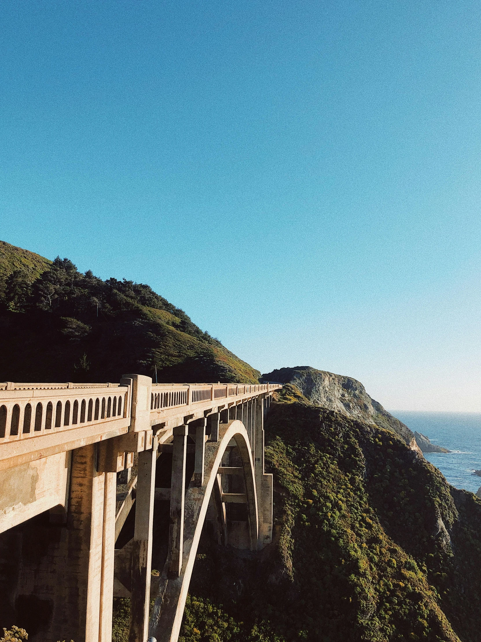 a bridge over a large body of water, a picture, by Kristin Nelson, pexels contest winner, hills and ocean, 2 5 6 x 2 5 6 pixels, road trip, profile image