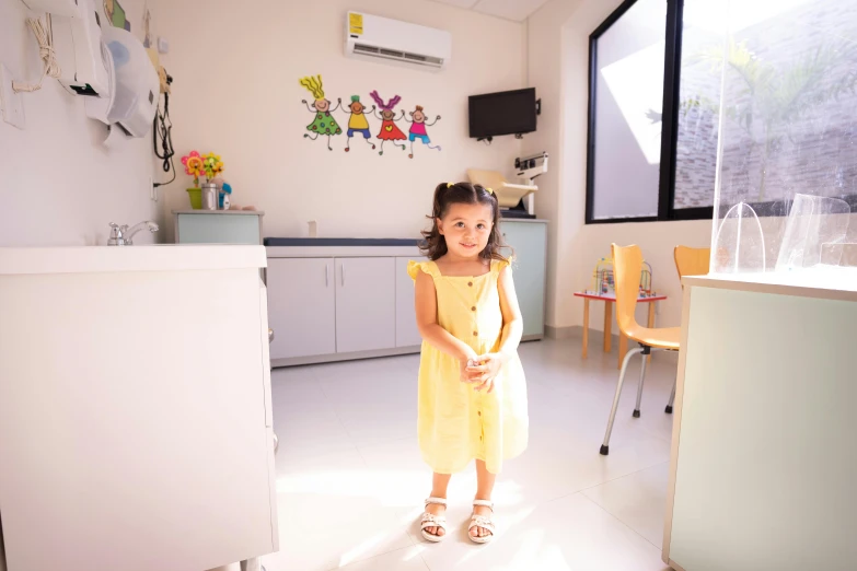 a little girl in a yellow dress standing in a room, a picture, by Lilia Alvarado, pexels contest winner, doctors office, sunny day time, cindy avelino, medical complex
