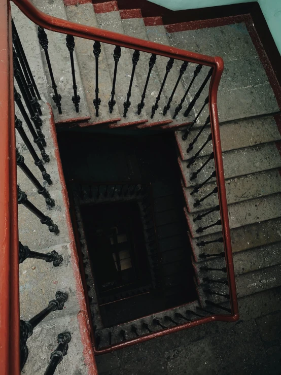 a close up of a spiral staircase in a building, an album cover, inspired by Elsa Bleda, pexels contest winner, baroque, black steel with red trim, high view, an escape room in a small, stairs to an upper floor