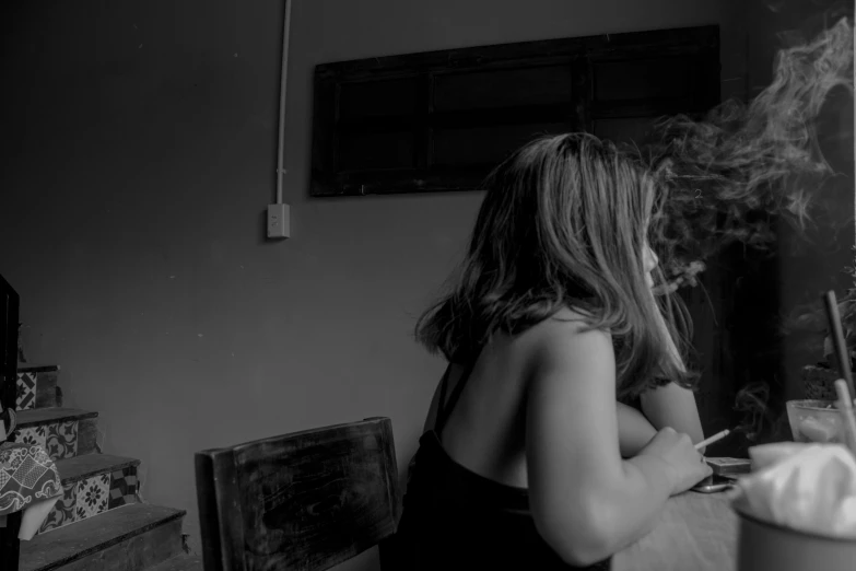 a woman sitting at a table smoking a cigarette, a black and white photo, unsplash, process art, showing her shoulder from back, romance, fernanda suarez, two women