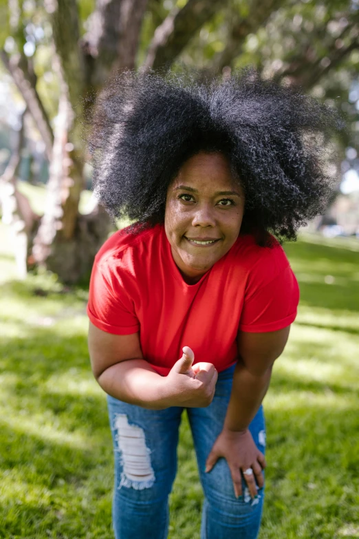 a woman standing in the grass with a frisbee, pexels contest winner, happening, natural hair, red t-shirt, square, plus size