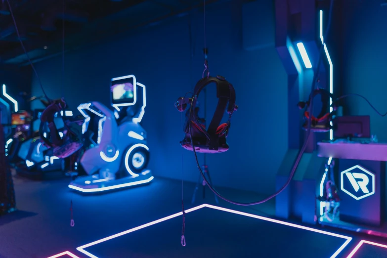 a room filled with lots of neon lights, inspired by Beeple, interactive art, robotic limbs on floor, hanging cables, gaming chair, neon blue