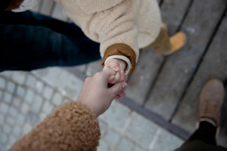 a close up of a person holding a child's hand, trending on pexels, happening, top down shot, happy couple, wintertime, cinematic shot ar 9:16 -n 6 -g