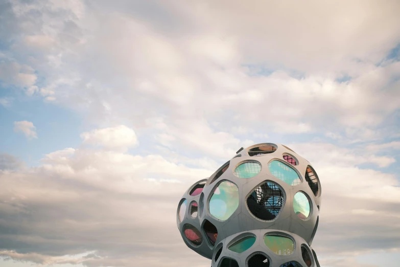 a large metal object sitting on top of a lush green field, unsplash contest winner, interactive art, trypophobia, reykjavik, cloudy skies, vibrant lights