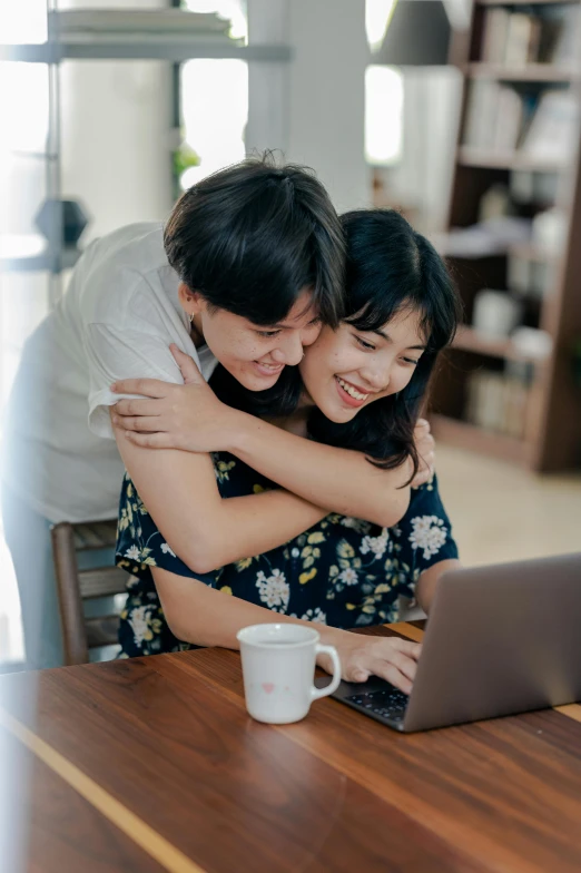 a man and woman hugging each other in front of a laptop, pexels contest winner, happening, asian female, malaysian, on a table, digital still