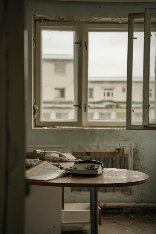 a wooden table sitting in front of a window, a portrait, by Elsa Bleda, unsplash, arte povera, an abandoned dystopian city, soviet town, table with microphones, in a decayed hospital room