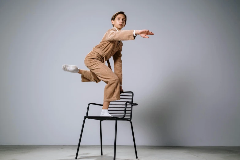 a woman jumping in the air on top of a chair, inspired by Peter de Sève, unsplash, arabesque, wearing human air force jumpsuit, brown clothes, default pose neutral expression, dezeen