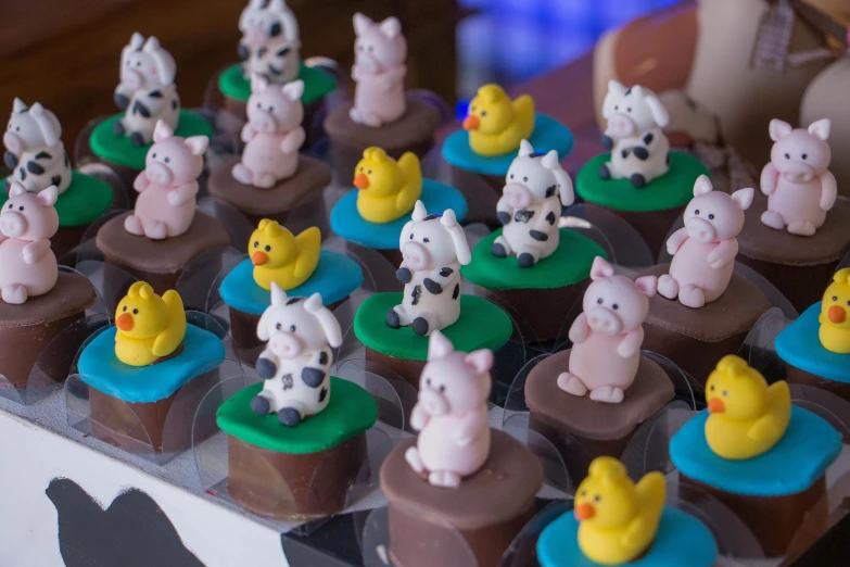 a close up of a tray of cupcakes with animals on them, a cartoon, 3 d clay figure, chocolate art, thumbnail, farm