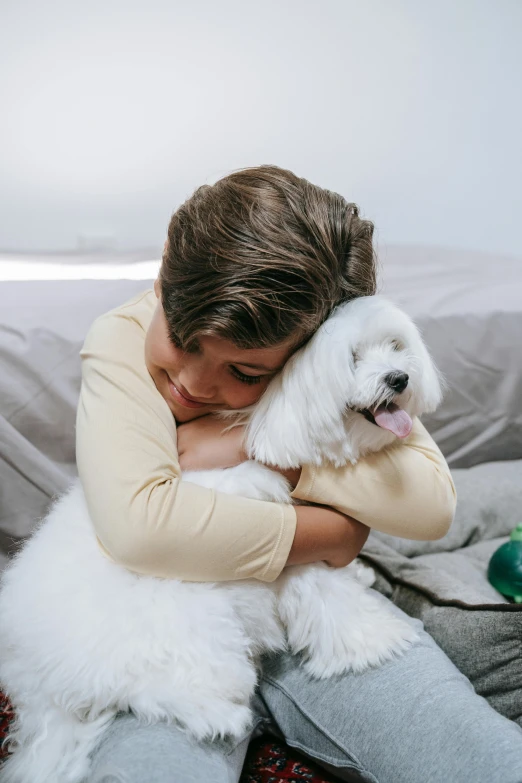 a woman sitting on a couch hugging a white dog, a stock photo, shutterstock contest winner, cute boys, havanese dog, supportive, instagram post