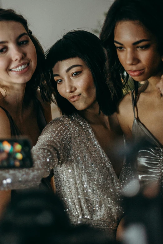 a group of women standing next to each other, a polaroid photo, trending on pexels, happening, wearing a sparkling dress, taking a selfie, in a silver silk robe, asian descent