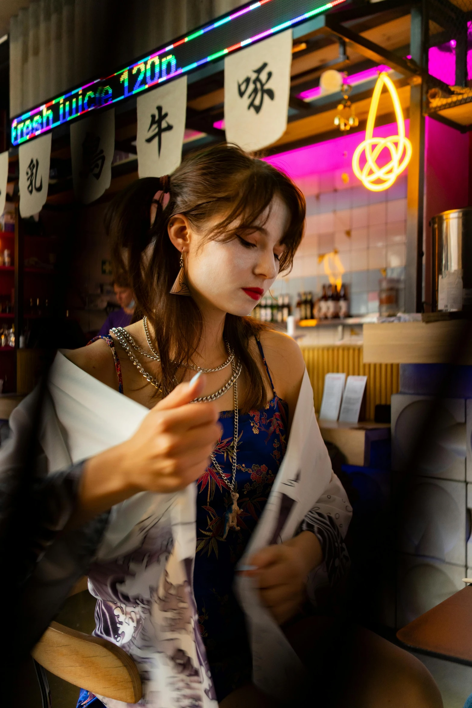 a woman sitting at a table reading a newspaper, by Julia Pishtar, pexels contest winner, photorealism, japanese neon signs, handsome girl, wearing a haori, market in japan