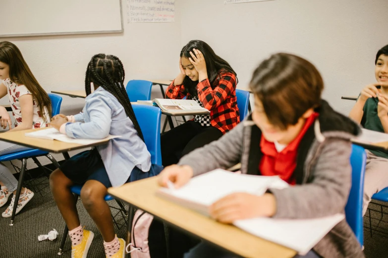 a group of children sitting at desks in a classroom, trending on unsplash, black haired girl wearing hoodie, full body image, thumbnail, background image