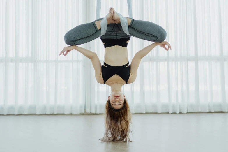 a woman doing a handstand on a pole, trending on pexels, arabesque, angel doing yoga in temple, hanging upside down, blank, in a jumping float pose