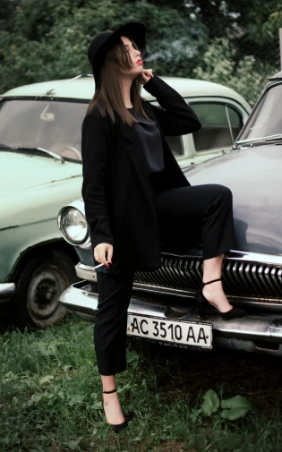 a woman sitting on the hood of a car, a picture, pexels contest winner, photorealism, ussr suit, casual black clothing, 15081959 21121991 01012000 4k, vouge style photo