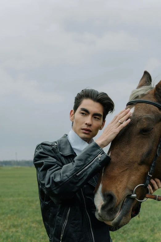 a man standing next to a horse in a field, an album cover, inspired by Zhang Han, trending on pexels, she wears leather jacket, photoshoot for skincare brand, non binary model, closeup portrait shot