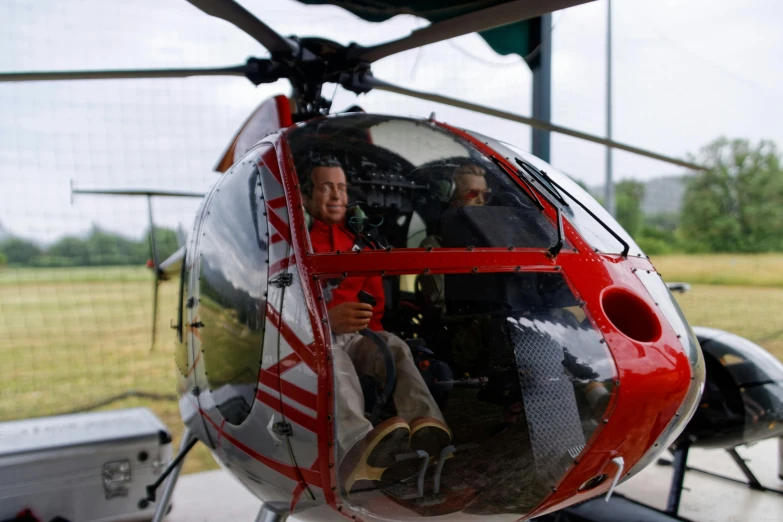 a red and white helicopter sitting on top of a tarmac, pexels contest winner, happening, with people inside piloting it, helmet view, 2010s, avatar image