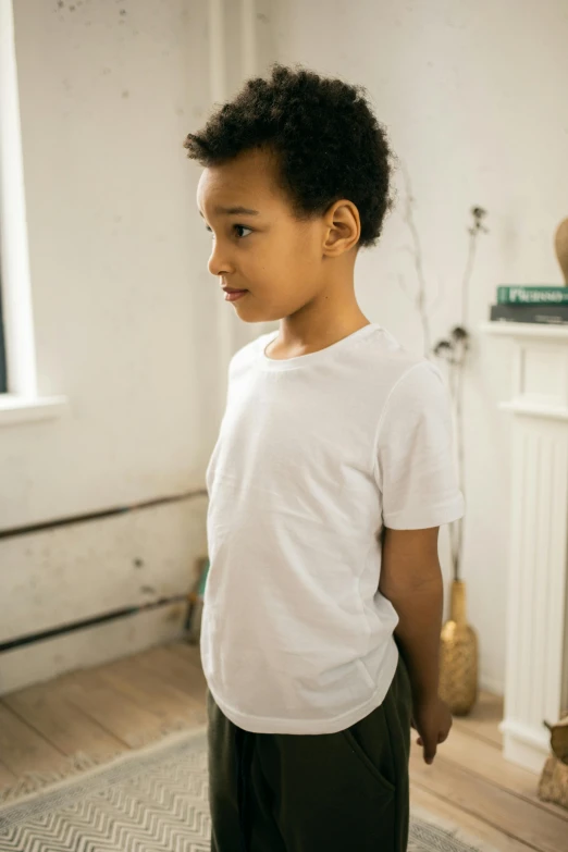 a young boy standing in a living room, by Nina Hamnett, pexels contest winner, happening, white tshirt, head turned to the side, pockets, no - text no - logo