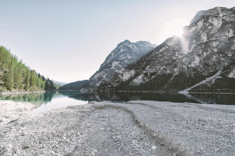 a large body of water surrounded by mountains, by Sebastian Spreng, pexels contest winner, minimalism, gravel and scree ground, dolomites in the background, early morning light, panoramic shot