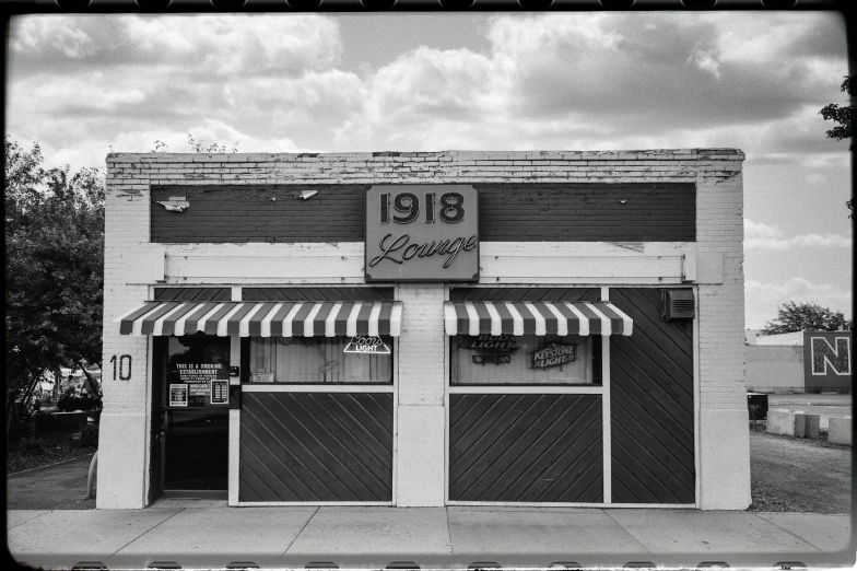 a black and white photo of a building, by Lee Loughridge, local bar, 1 6 x 1 6, nostalgic 8k, storefront