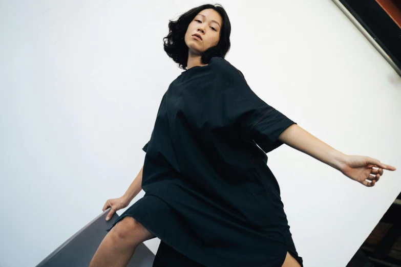 a woman in a black dress standing on an escalator, inspired by Gao Cen, unsplash, happening, wearing a hospital gown, studio shoot, issey miyake, wearing a black t-shirt