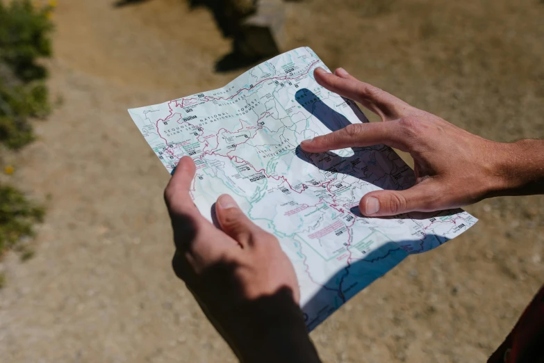 a person holding a map in their hands, by Jessie Algie, unsplash, instagram post, trecking, rectangle, foil