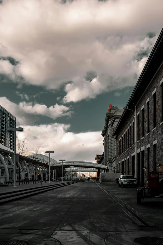 a train traveling down train tracks next to tall buildings, pexels contest winner, dry archways and spires, altostratus clouds, shipyard, square