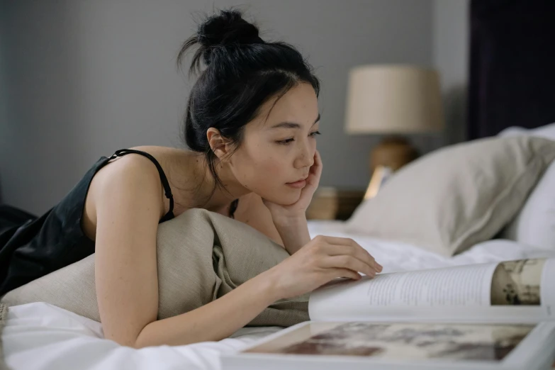 a woman laying on a bed reading a book, a drawing, pexels contest winner, asian descent, looking from side, profile image, good posture