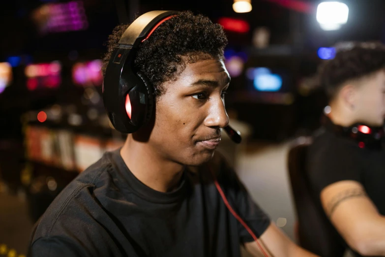 a man wearing headphones sitting in front of a computer, team ibuypower, close up head shot, a busy arcade, mkbhd