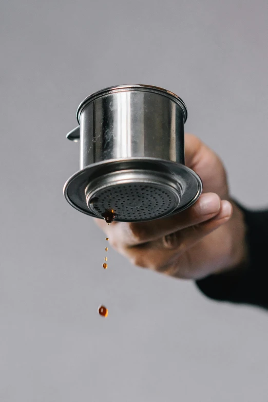 a close up of a person holding a strainer, by Ben Zoeller, top lid, spilling juice, hibernation capsule close-up, coffee stain