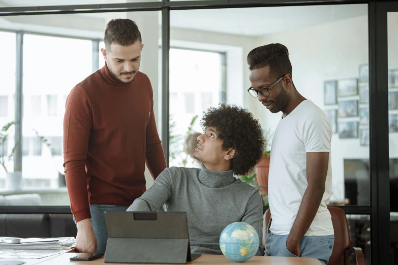 a group of people standing around a table with a laptop