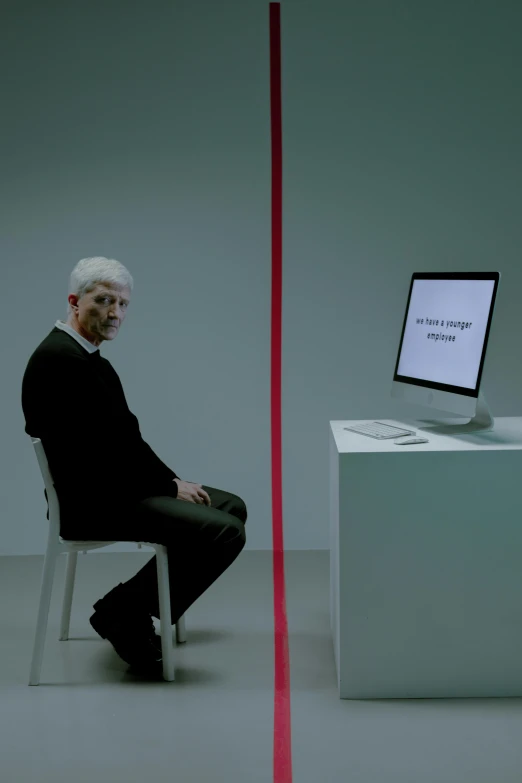 a man sitting in a chair in front of a computer, a hologram, by Marina Abramović, a silver haired mad, ignant, award winning ad, apple