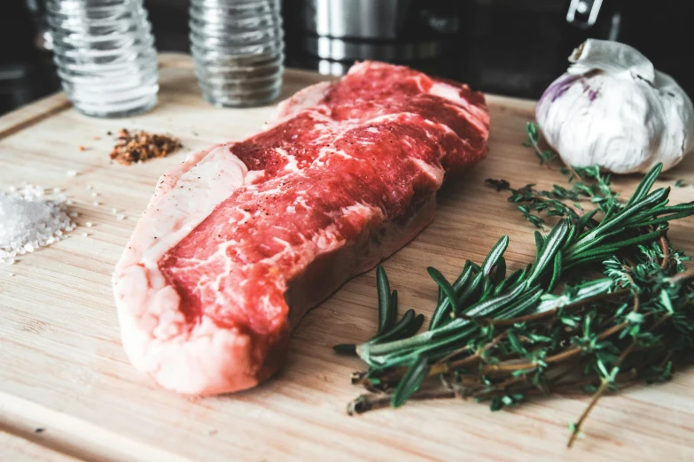 a piece of meat sitting on top of a wooden cutting board, bay area, informative guide, epicurious, on a table