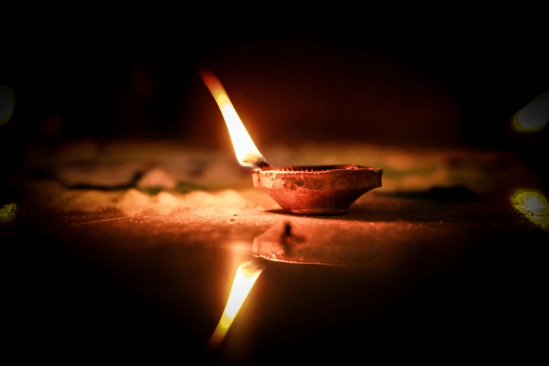 a lit candle sitting on top of a table, pexels contest winner, light and space, indian temple, fire reflection, torch, print ready