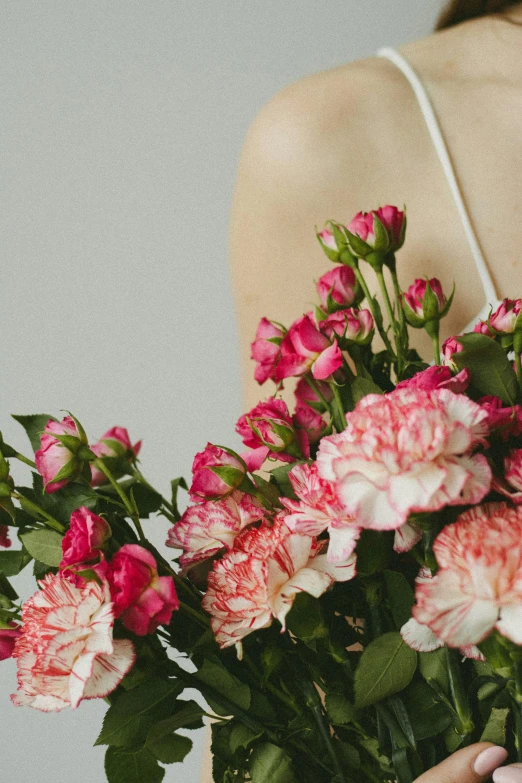 a woman holding a bouquet of pink and white flowers, a still life, by Elsie Few, trending on unsplash, graceful body structure, carnation, neck zoomed in, detail shot