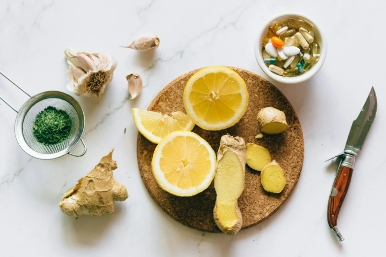 a wooden cutting board topped with sliced lemons, a still life, trending on pexels, drinking cough syrup, ginger, greens, tea