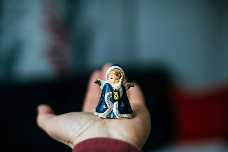 a small figurine of an angel on a person's hand, inspired by Louis Le Nain, pexels contest winner, cloisonnism, little boy wearing nun outfit, a small, religious, on a canva